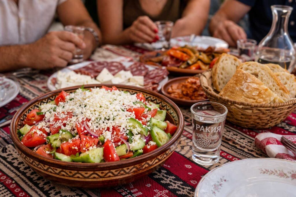 Shopska salad served with a glass of rakia and traditional Bulgarian meze
